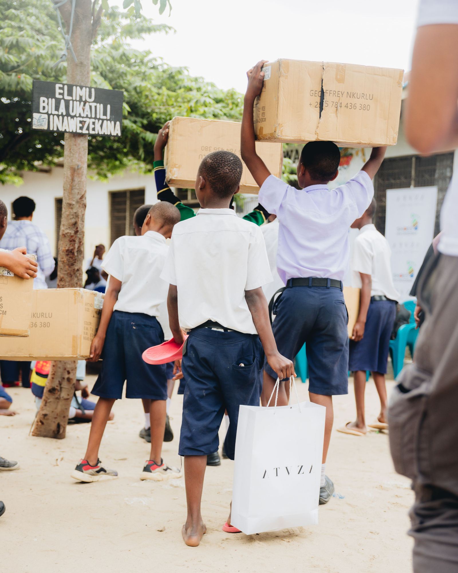 Students carrying boxes of new shoes across a schoolyard
